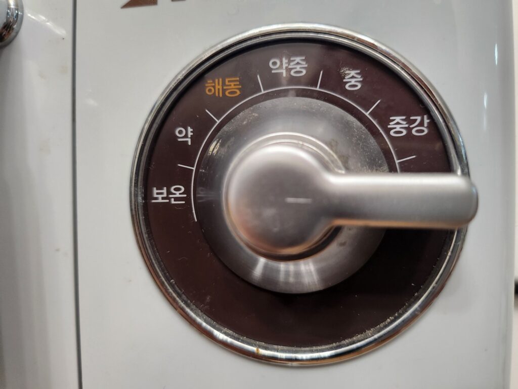 A metal kitchen dial with Korean heat settings from "keep warm" to "medium-high" — a metaphor for ADHD emotional dysregulation, where the volume dial is stuck too high.