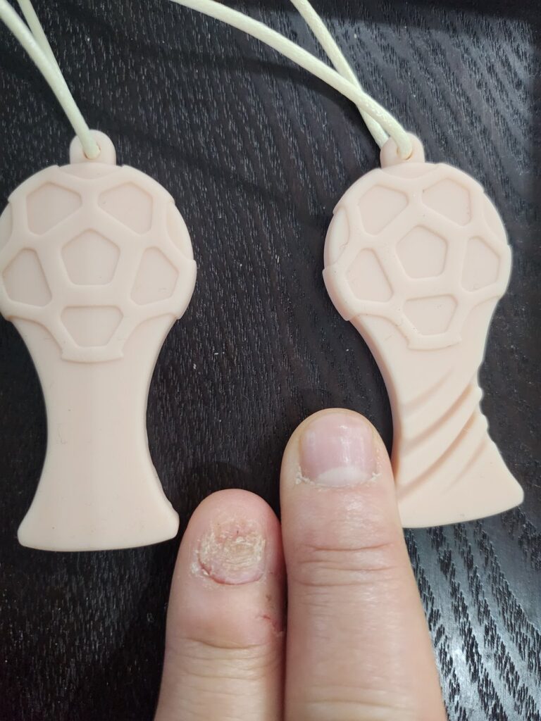 Two silicone chewable necklaces (chewies) next to bitten nails